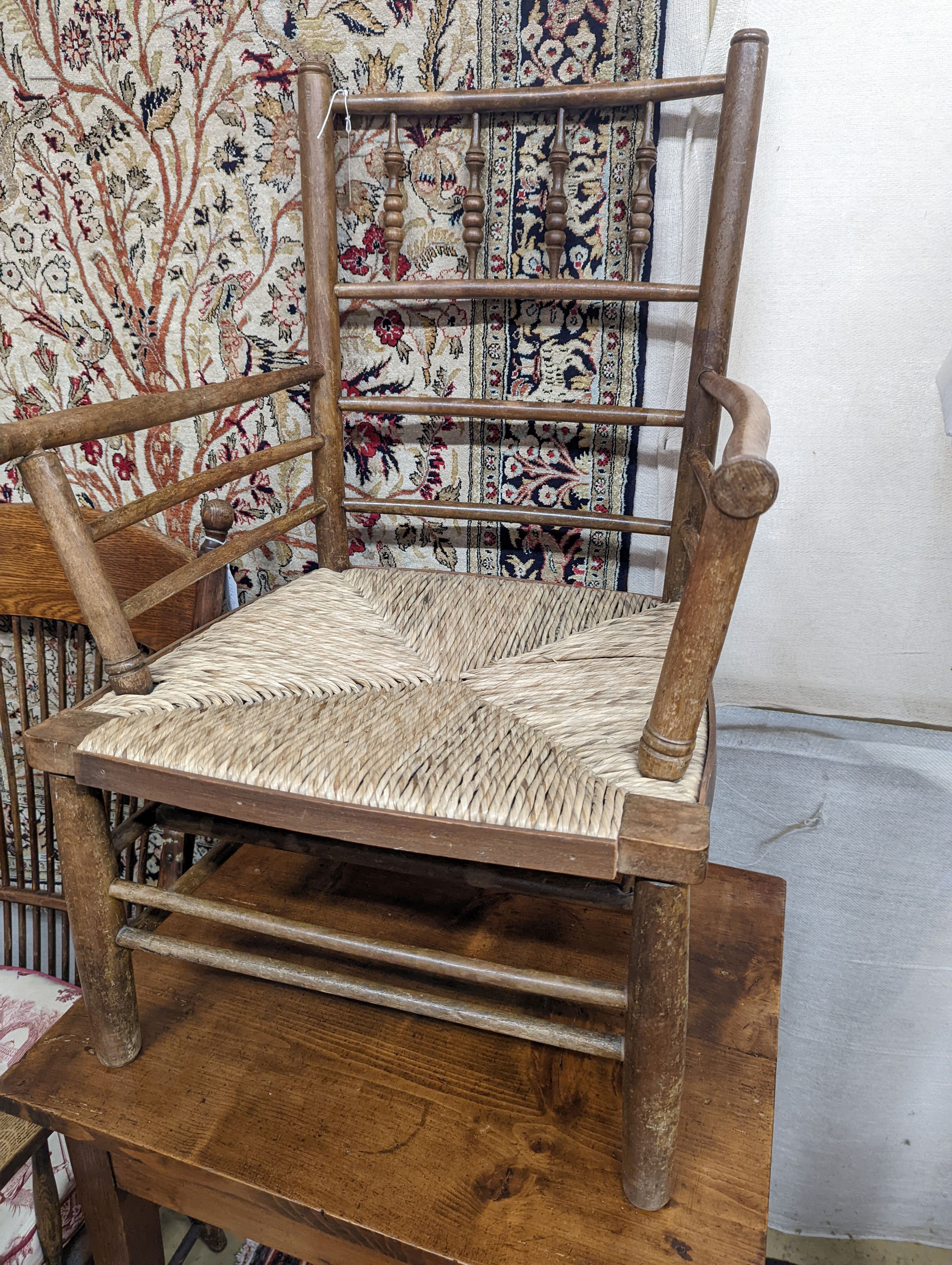 A late 19th century beech rush seated Sussex elbow chair, (cut down) width 55cm, depth 44cm, height 81cm